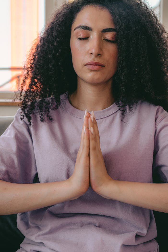 Mastering the First Impression: Your intriguing post title goes here Peaceful woman in a crew neck t-shirt meditating indoors with hands together.